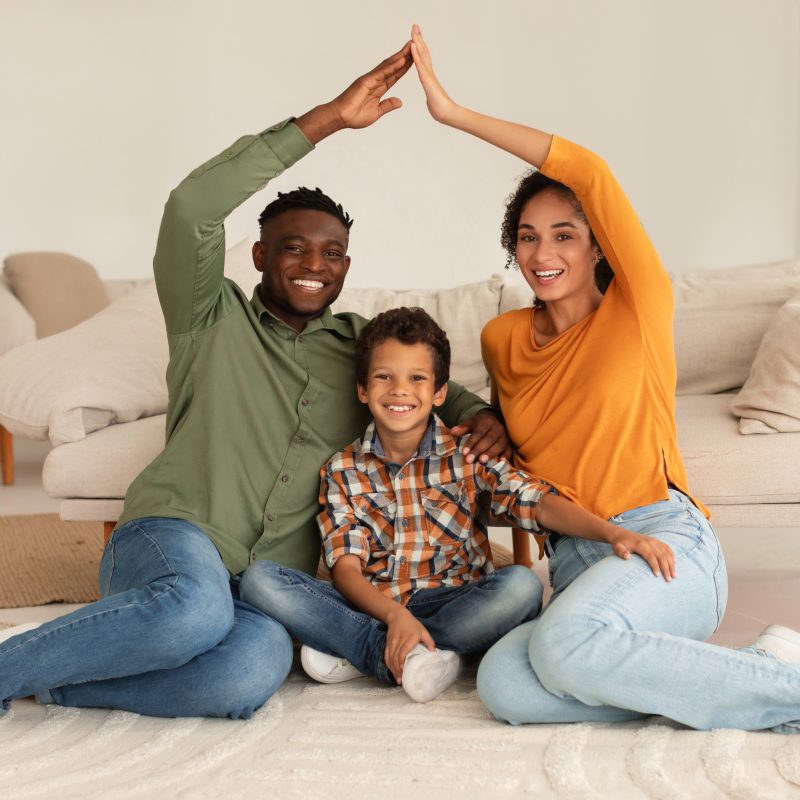 Happy Diverse Parents Making Symbolic Roof Above Son At Home