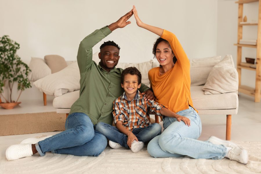 Happy Diverse Parents Making Symbolic Roof Above Son At Home